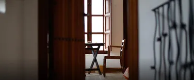 Wooden table and chair by a window, glimpsed through a half-open door