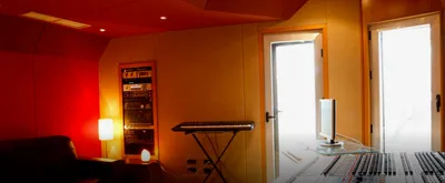 Control room with an outboard rack, keyboard stand and mixing desk in the foreground