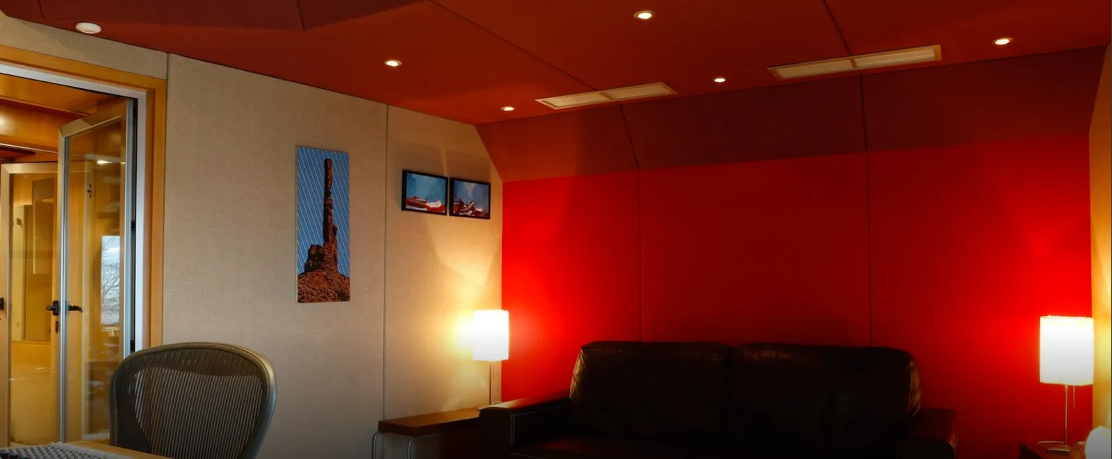 Control room lounge with a red wall, black leather sofa and glowing lamps