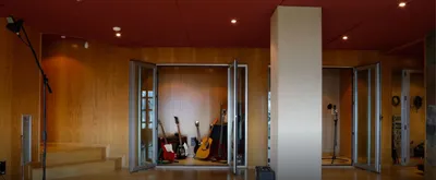 Isolation booths with open glass doors, one filled with guitars and amps