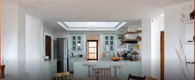 Open kitchen with a skylight, pale green cabinets, breakfast bar and stools