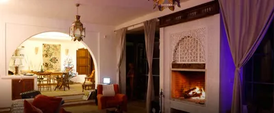 Living room at night with a lit carved-plaster fireplace and an arch to the dining area