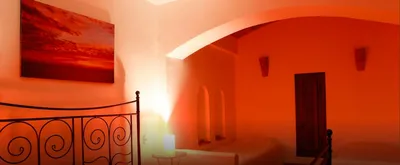 Bedroom in warm orange light with a wrought-iron bed and arched niches