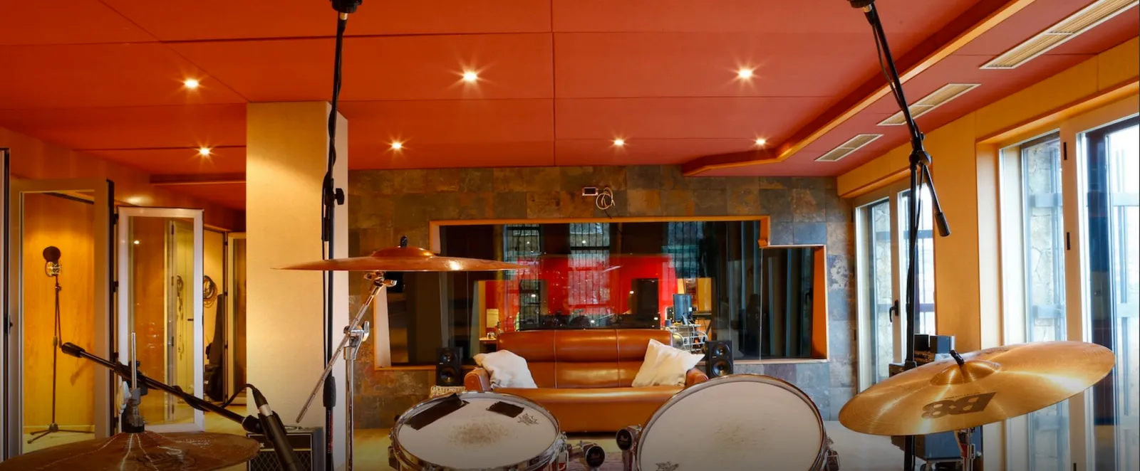 Live room seen from behind the drum kit, control room window beyond